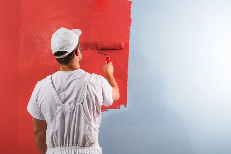 Malerarbeiten Maler streicht eine Wand rot